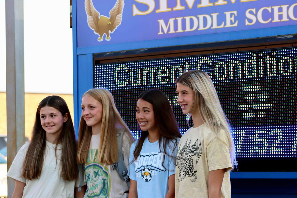 Four girls standing in front of the Simmons Middle School sign